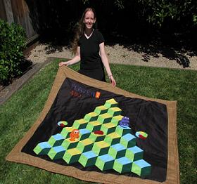 Woman holding quilt with Q-Bert game image