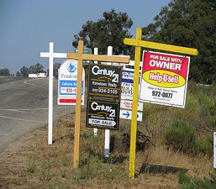 Real estate for sale signs near street