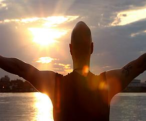 man facing sunshine with arms outstretched
