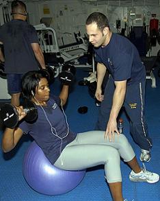Woman on exercise ball with physical fitness trainer